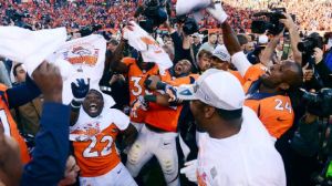 Professional football players for the Denver Broncos in orange uniforms celebrate their win of the AFC Championship.